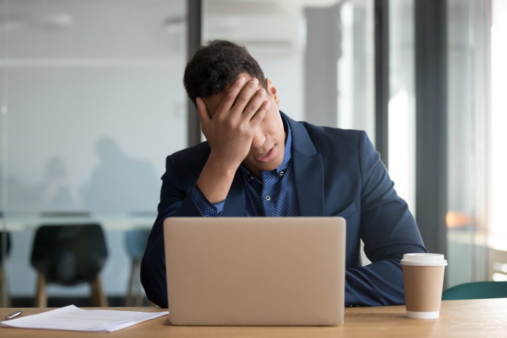 Frustrated business owner at desk with laptop, representing challenges in managing Google Business Profile visibility and disappearing Google Posts in local search