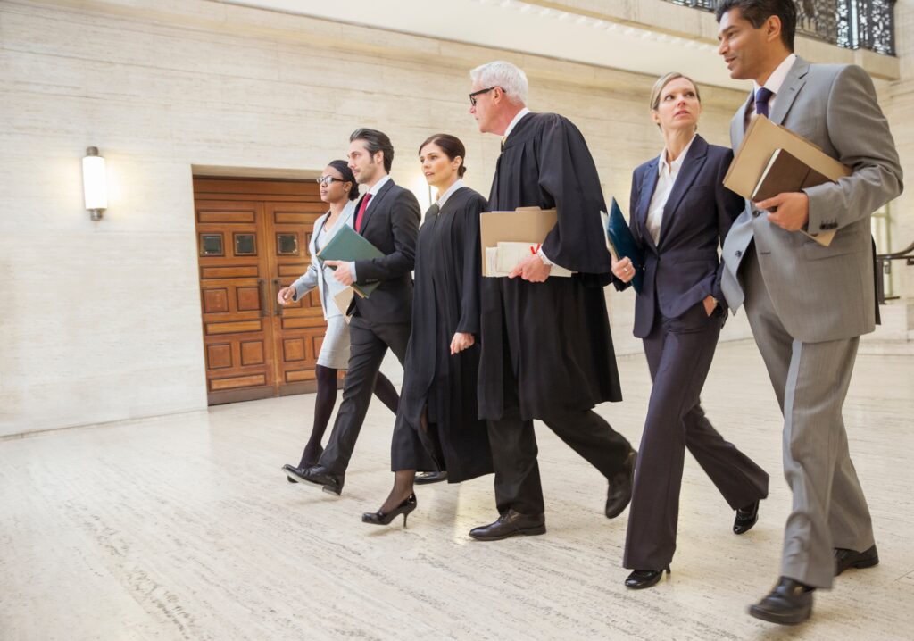 A diverse group of legal professionals, including judges and attorneys, confidently walking through a courthouse hallway, symbolizing legal collaboration and expertise.
