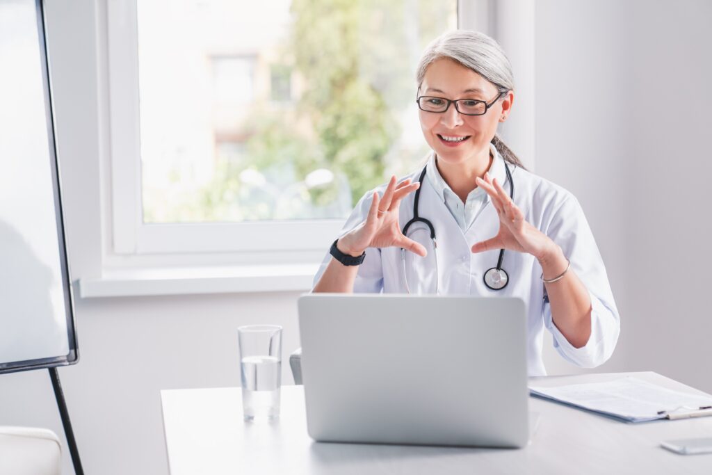 Smiling female doctor conducting a virtual consultation via laptop, representing healthcare communication and telemedicine marketing strategies.