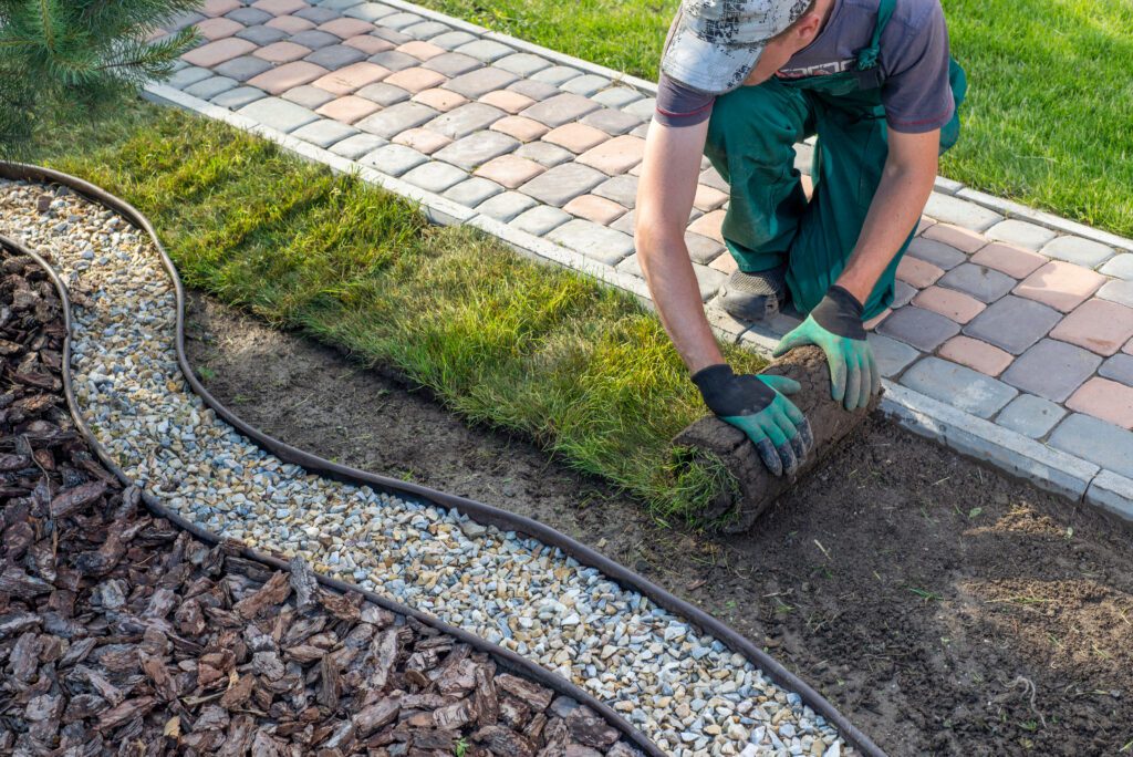 Landscaper installing fresh sod along a decorative garden border, representing local landscaping services and home improvement for increased curb appeal and local search visibility.