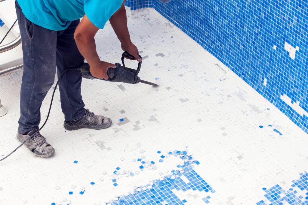 Pool technician using power tools for tile renovation—demonstrating seasonal demand for pool remodeling services and the need for high-visibility digital marketing campaigns in summer