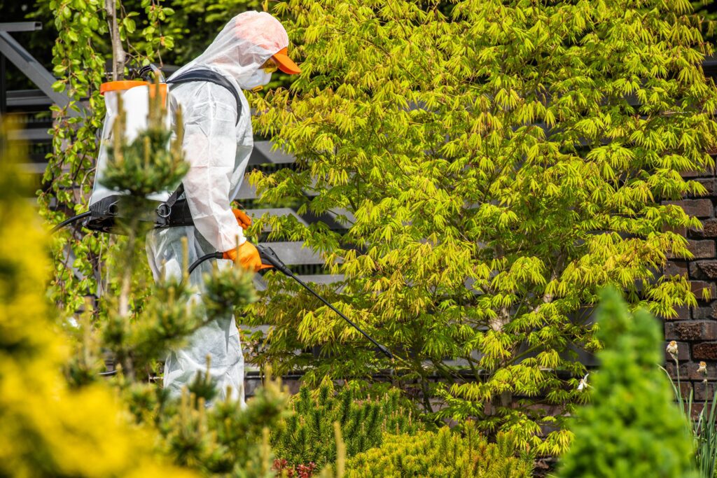 Pest control technician in protective gear performing summer treatment—representing seasonal service surges and the importance of reputation management, local advertising, and targeted campaigns.