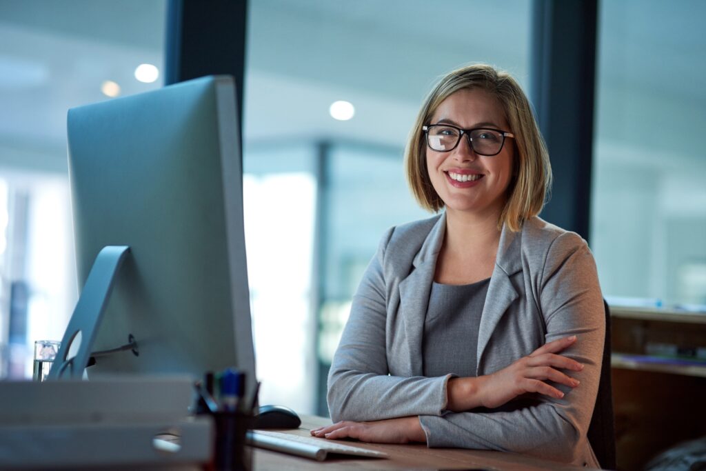 Smiling attorney at law firm desk engaging with legal content marketing and digital strategy on a desktop computer, representing professional services in the legal industry.