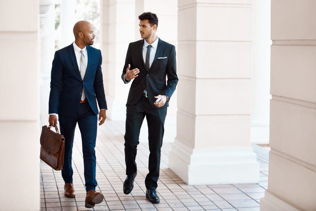 Lawyers in business attire discussing client acquisition and legal blogging strategies, symbolizing thought leadership, firm visibility, and reputation management in the legal field.