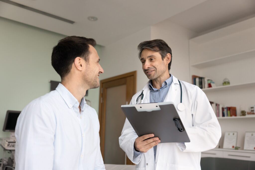 Physician discussing patient health data and treatment plan with male patient in modern clinic—highlighting personalized healthcare, patient satisfaction, and responsive healthcare website communication strategies.