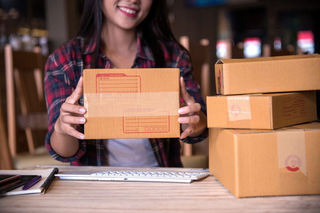 Ecommerce seller preparing product shipments with cardboard boxes, representing Amazon FBA logistics, online retail fulfillment, and inventory management for PPC advertising success