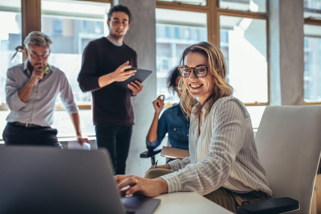 Smiling ecommerce marketing team discussing digital marketing strategy, customer acquisition cost, and conversion optimization in modern agency office