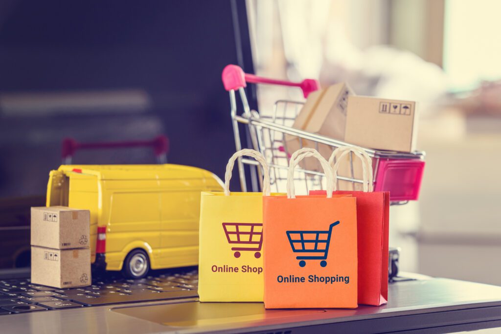 Colorful online shopping bags, miniature delivery van, and shopping cart on a laptop keyboard symbolizing ecommerce marketing, cart abandonment recovery, and subscription-based order fulfillment.