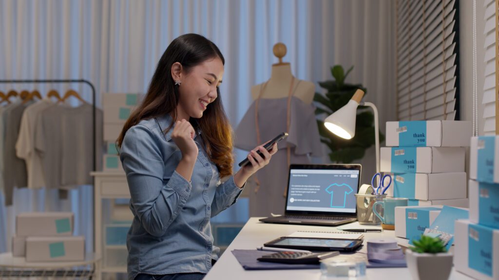 Happy ecommerce business owner celebrating online sales success, showcasing ROI from influencer marketing, SMS marketing, and loyalty program growth
