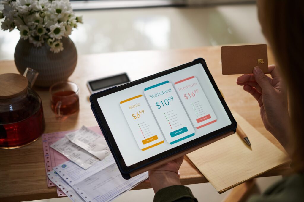 Person reviewing subscription plan pricing tiers on a tablet, showcasing flexible pricing strategies, customer onboarding, and subscription business model customization to reduce churn rates.