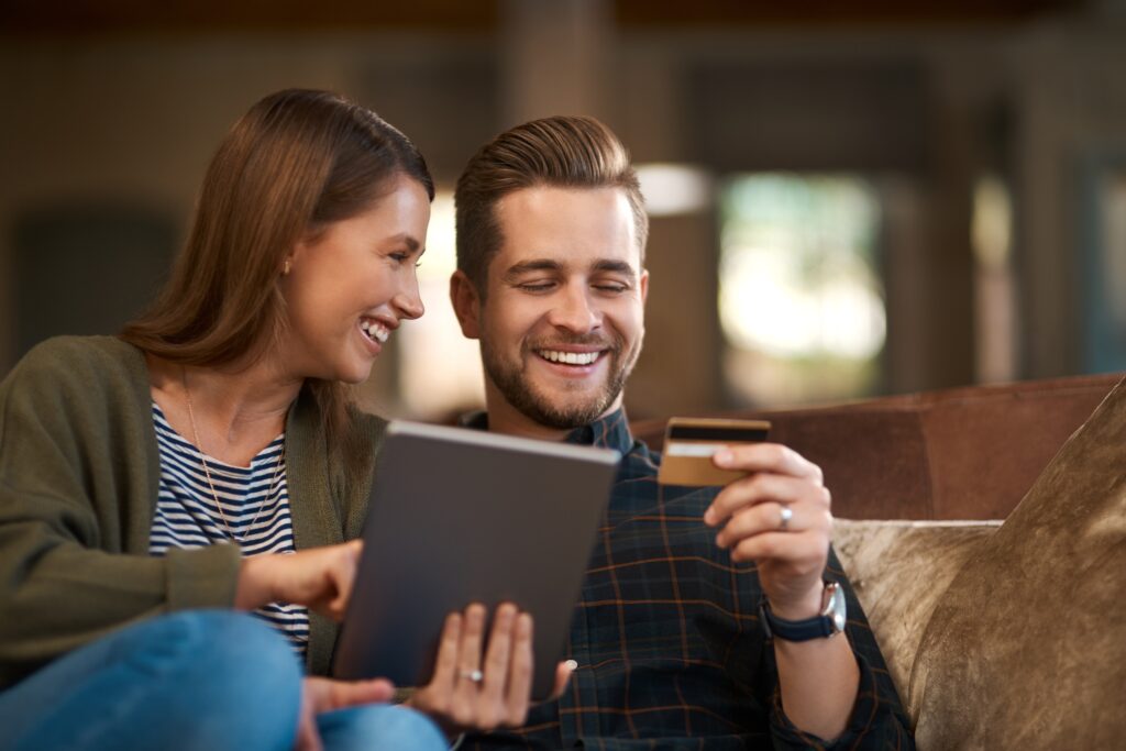 Smiling couple shopping online using a tablet and credit card, representing ecommerce customer engagement, subscription purchases, and digital marketing automation for online shopping.