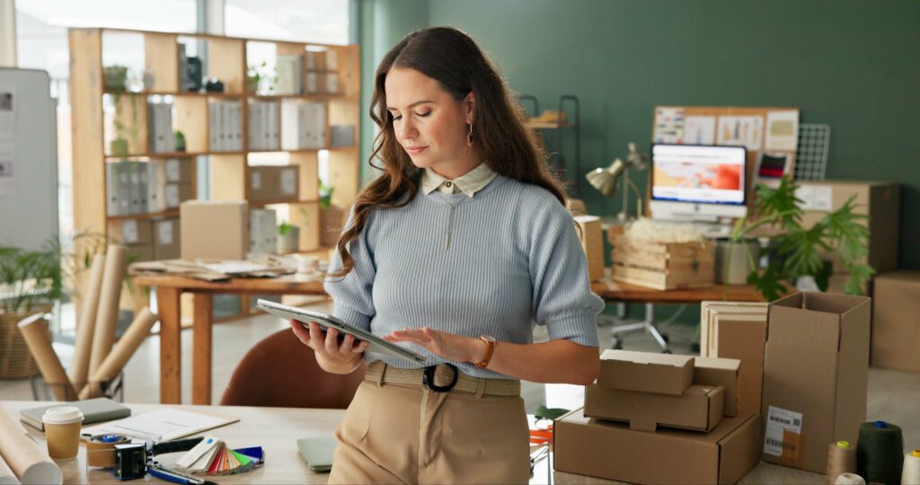Female ecommerce business owner using a tablet in a modern office, highlighting ecommerce SEO strategies, inventory management, product page optimization, and content strategy development.
