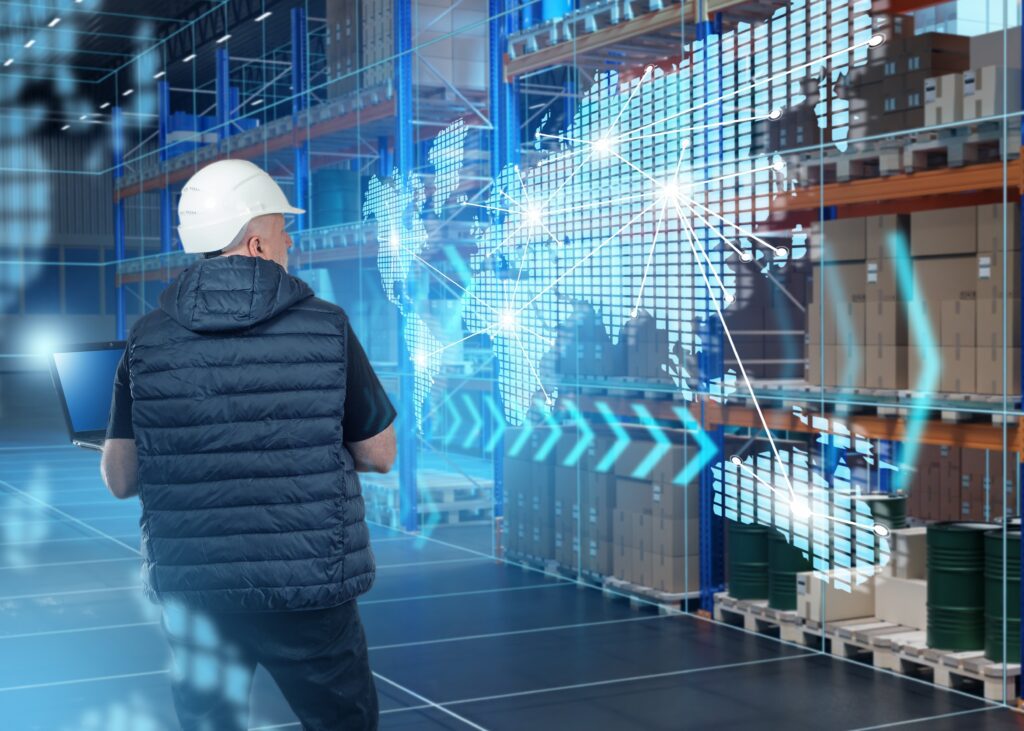 Warehouse manager using laptop with global supply chain visualization overlay—symbolizing real-time backend visibility, inventory management software, and international ecommerce fulfillment solutions for streamlined logistics and distribution.