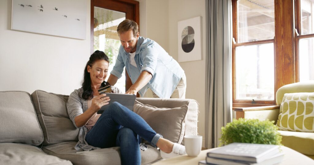 Happy couple shopping online from a tablet at home, illustrating seamless ecommerce user experience, secure online shopping, and optimized mobile checkout for improved conversion rates.