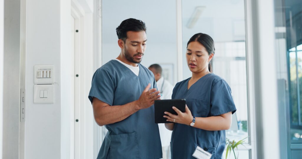 Medical staff in scrubs reviewing patient data on a tablet, optimizing healthcare clinic performance through SEO, web design, and digital strategy.