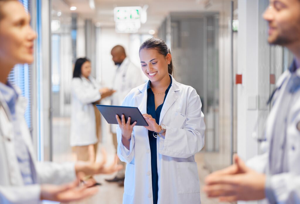 Smiling physician using tablet for patient data analysis and engagement powered by artificial intelligence and healthcare chatbot technology in a modern health system.