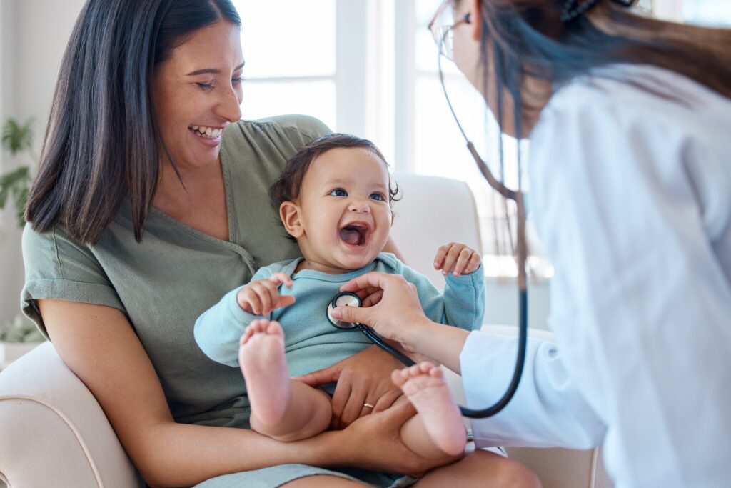Happy mother holding her baby during a pediatric check-up, showcasing positive patient experience, compassionate healthcare, and trust in family medicine — a core concept in healthcare marketing and patient satisfaction.