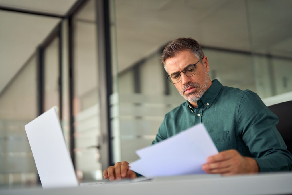 Senior consultant analyzing digital marketing performance reports at office desk, evaluating ROI from SEO services and PPC campaigns for law firms and professional service providers.