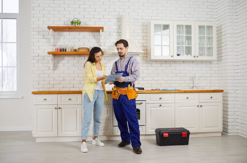 Plumber showing paperwork to a homeowner in a modern kitchen, highlighting trust and customer service in home services referral programs.
