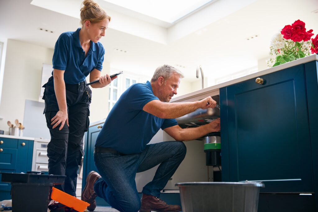 Plumbing technician and customer discussing emergency plumbing services in a modern kitchen, highlighting customer engagement and the importance of local SEO for plumbing companies.
