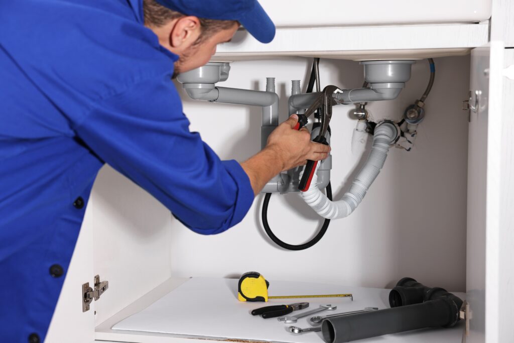 Professional plumber performing drain cleaning and pipe repairs under a kitchen sink, representing residential plumbing services and lead generation through Google Local Service Ads.